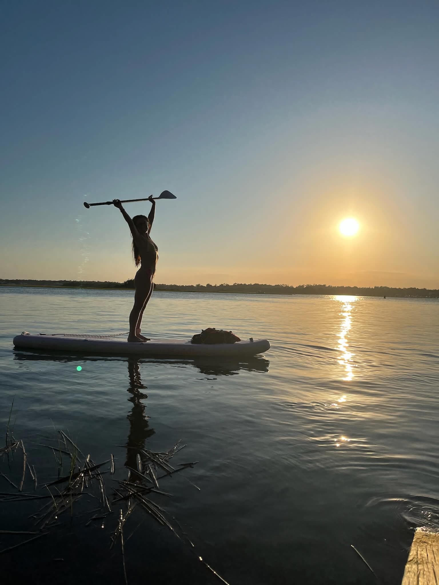 Paddleboarder celebrating at sunset on the water